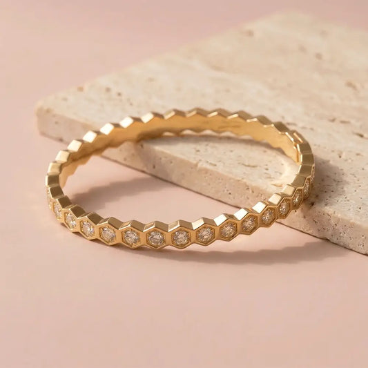 Hexagon crystal gold bracelet with diamond-like stones placed on beige stone surface, sleek geometric design.