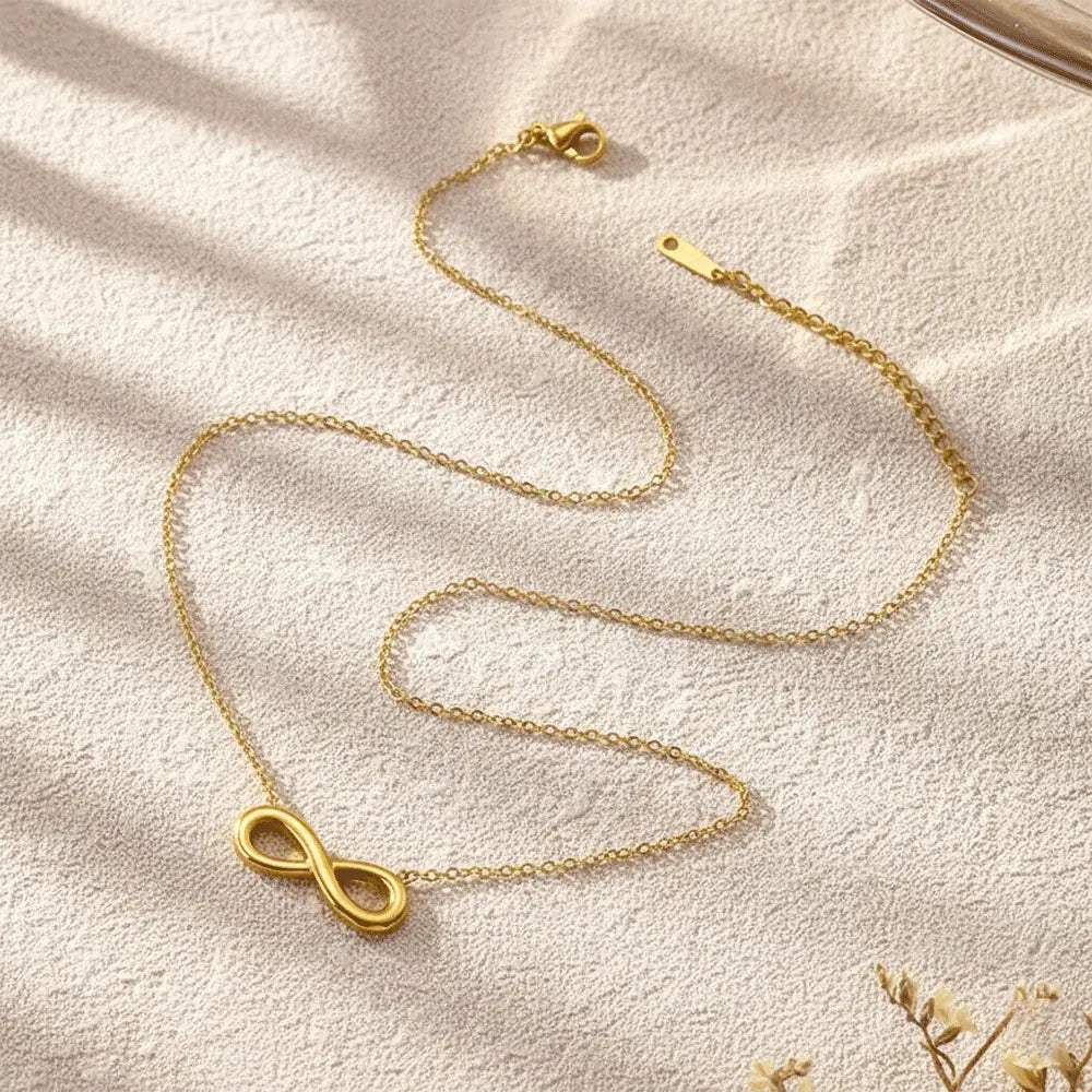 K-A Trends anti tarnish gold infinity pendant necklace on beige textured background minimalist jewellery flatlay