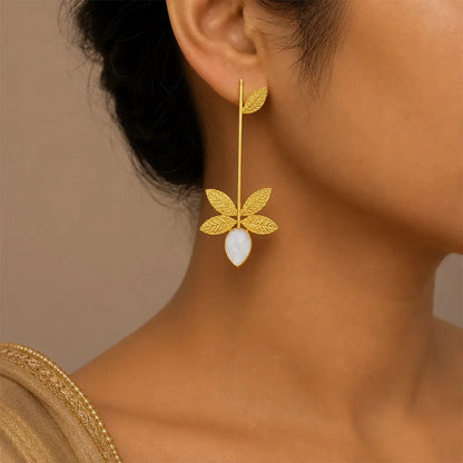 Indian model wearing Ivory Leaf anti tarnish brass earrings featuring textured gold leaf motifs and a white teardrop stone.