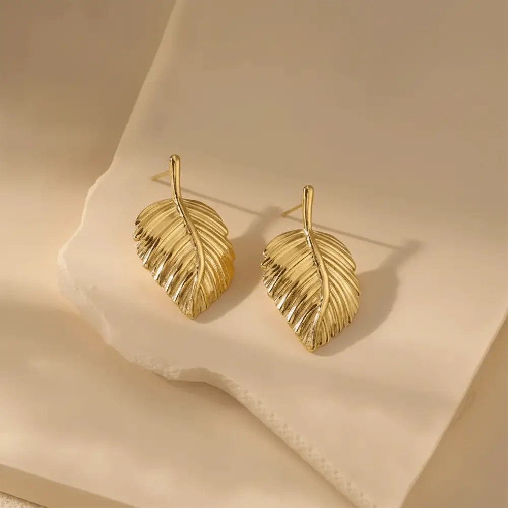 K-A Trends anti tarnish gold leaf stud earrings on cream fabric luxury aesthetic product photography