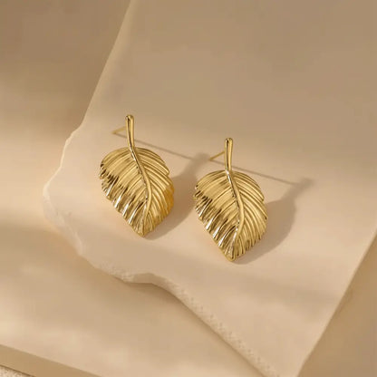 K-A Trends anti tarnish gold leaf stud earrings on cream fabric luxury aesthetic product photography