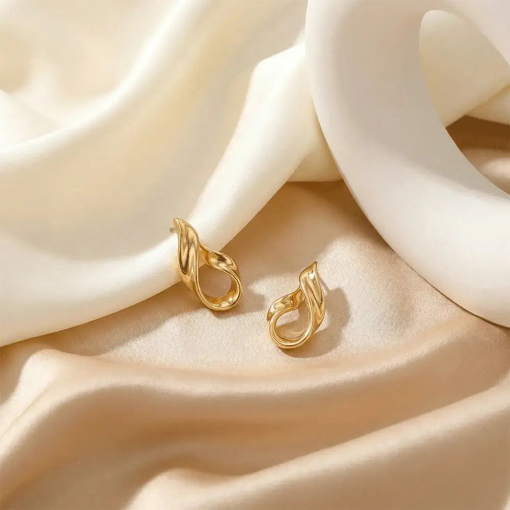 Luxury liquid gold stud earrings on flowing white fabric background, anti tarnish gold earrings for daily and party wear
