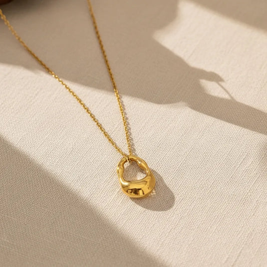 Dainty gold-plated necklace featuring a textured, irregular, molten metal pendant.
