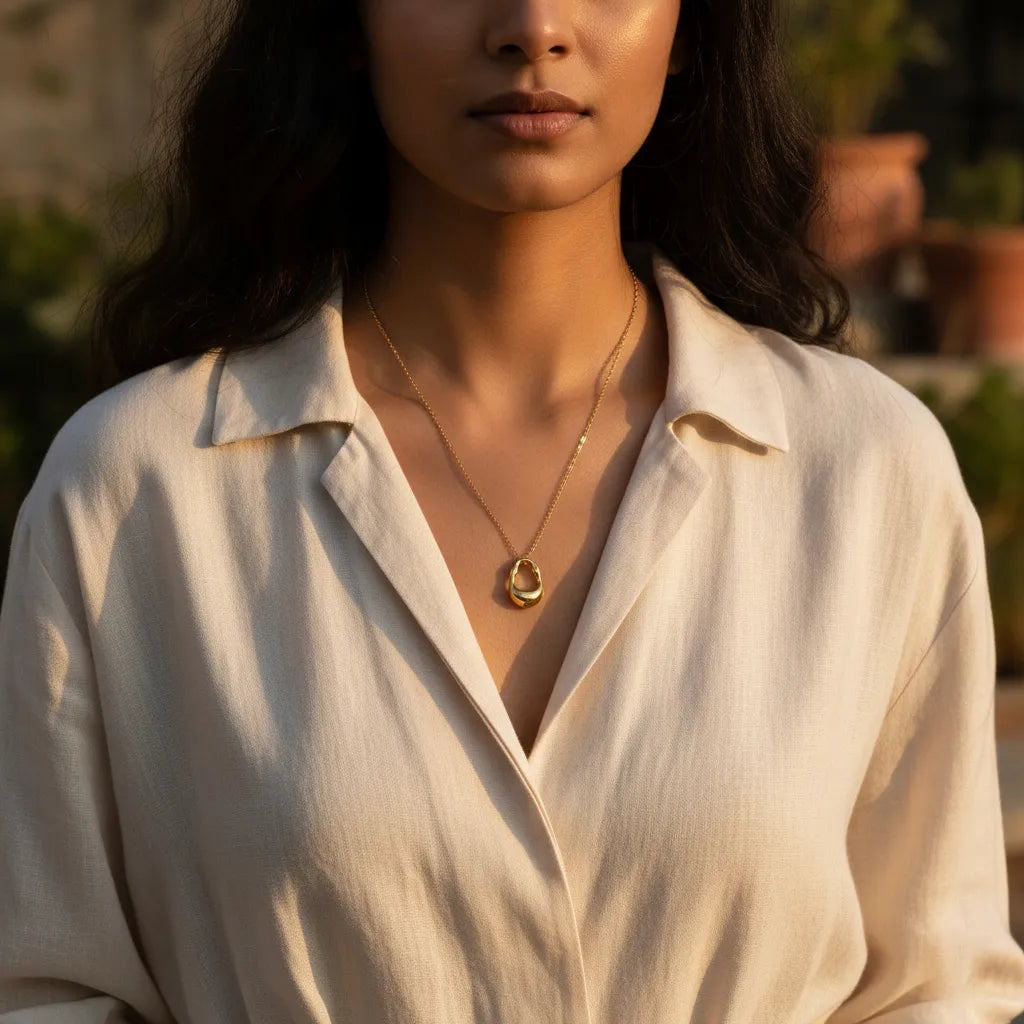 Dainty gold-plated necklace featuring a textured, irregular, molten metal pendant.