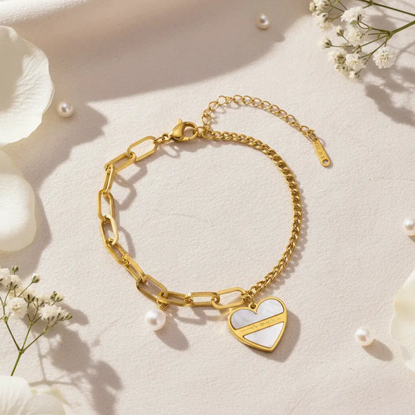 Love Chain Bracelet with gold chain links, pearl charm, and white heart pendant displayed on a soft floral background.
