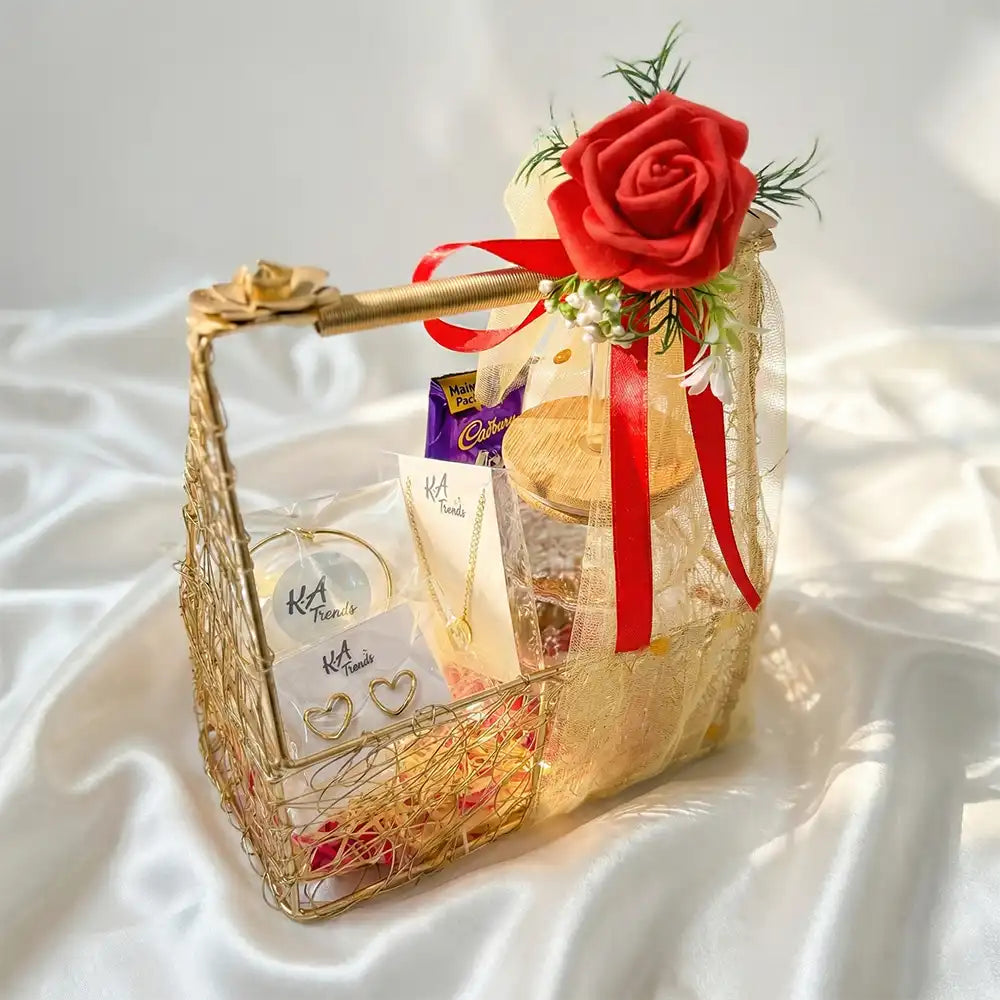Valentine luxury jewellery hamper featuring anti-tarnish heart-shaped earrings, delicate bracelet, pendant necklace, chocolates, and fairy lights, styled in a gold wire basket with red rose décor.