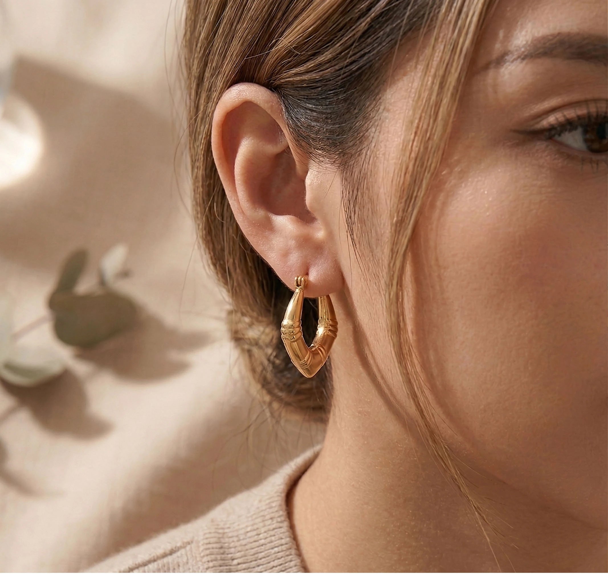 Close-up of a person wearing Luxe Arc Hoops with a soft background