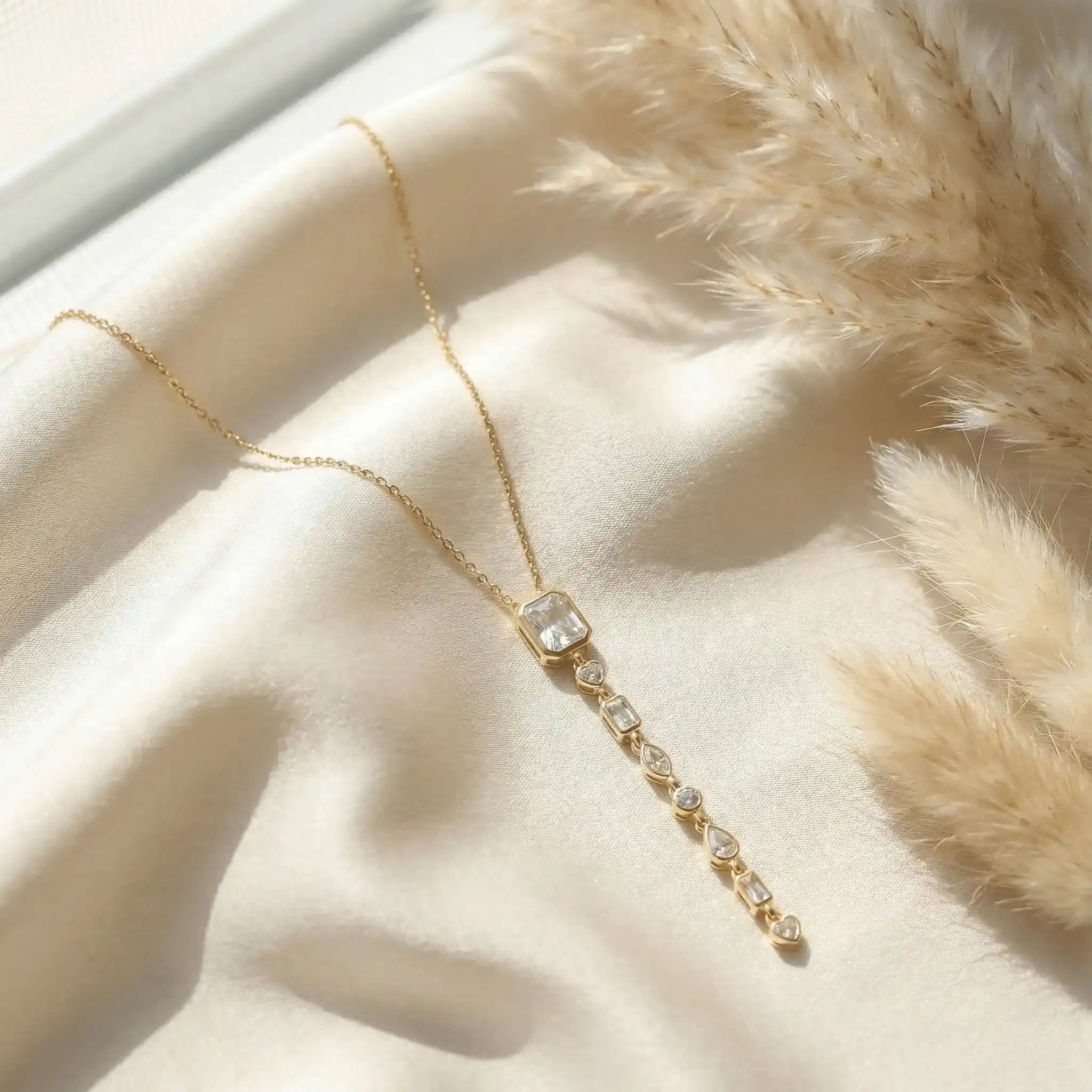 Elegant gold multi stone drop pendant necklace with crystal detailing on white satin background – anti tarnish jewellery