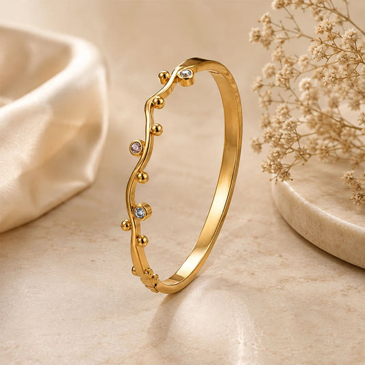 Multistone Tulip Kada with a wavy line design, small gold bead accents, and two clear rhinestone details, displayed on a beige marble surface with soft cream fabric and dried flowers.