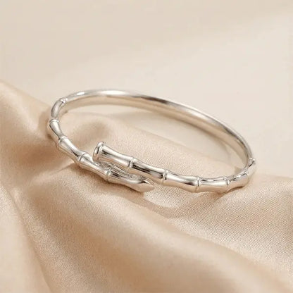 Nail Bracelet anti-tarnish silver-tone bracelet displayed on soft beige satin fabric with minimal luxury styling