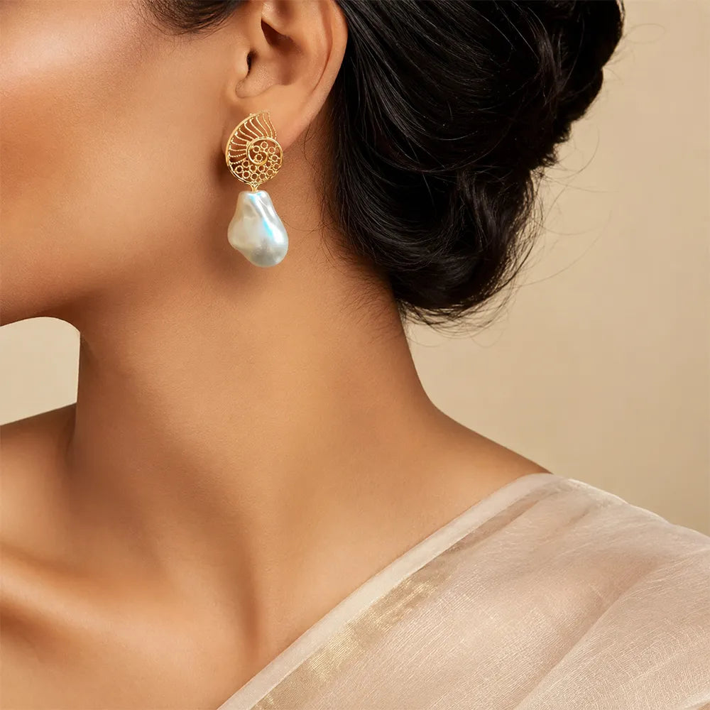 Indian model wearing Ocean Spiral anti tarnish brass earrings with intricate gold spiral design and statement baroque pearl drops.