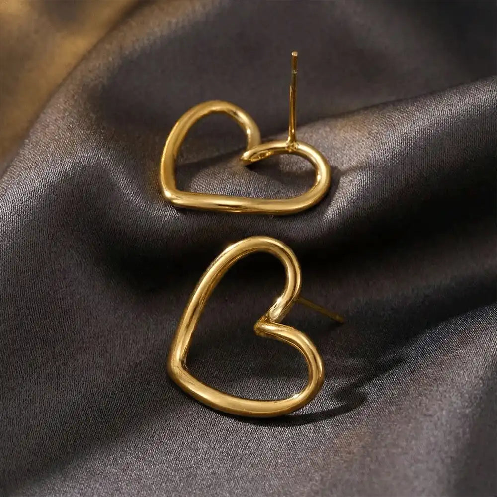 Open heart gold stud earrings placed on dark satin fabric, highlighting the smooth heart outline and polished anti-tarnish finish.