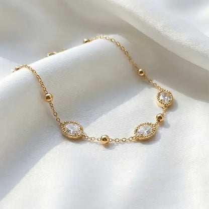Anti-tarnish gold oval stone chain bracelet with zircon stones, delicate minimalist jewellery displayed on white satin fabric