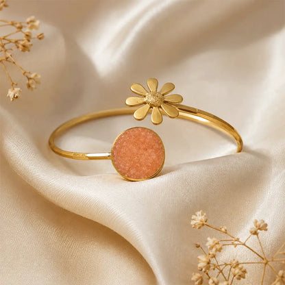 Peach Blossom anti tarnish brass bracelet with peach druzy crystal and gold daisy flower detail displayed on an ivory satin background.