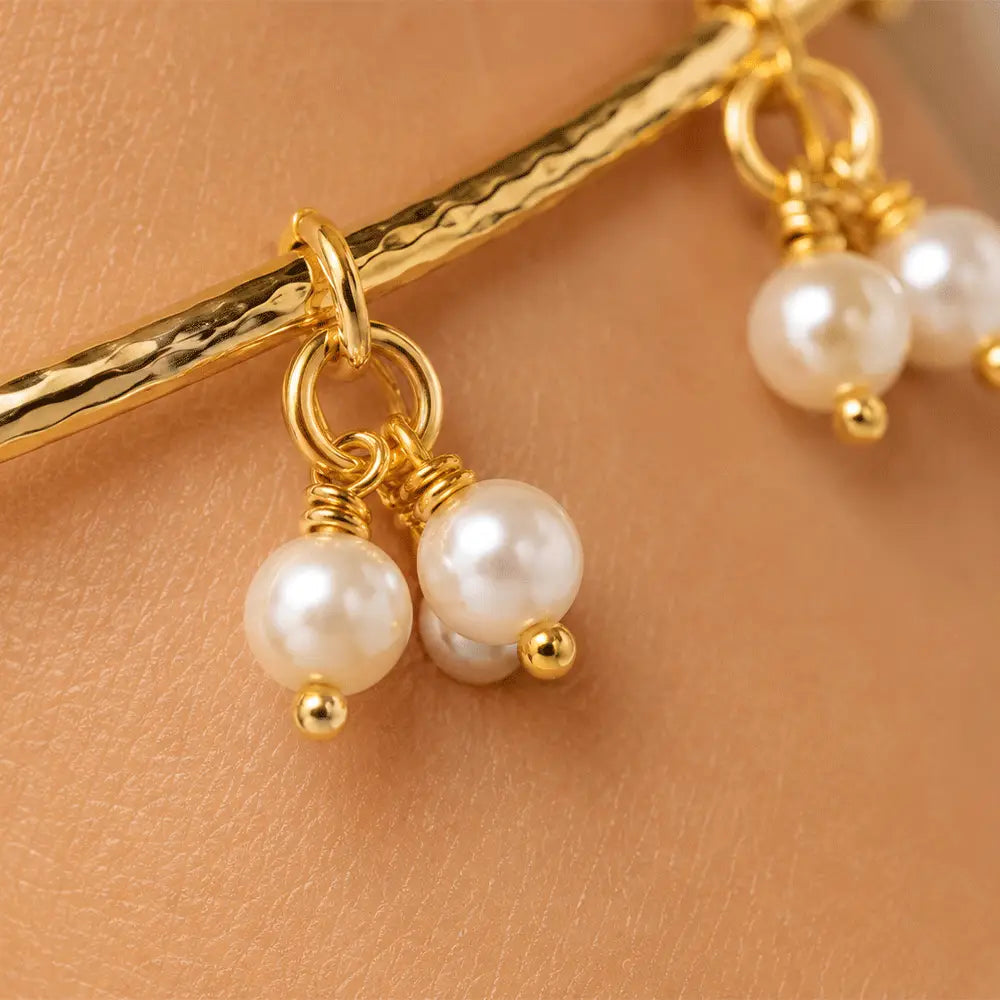 Macro close-up of Pearl Charm anti tarnish brass bracelet featuring dangling pearl cluster charms suspended from a textured gold-toned open bangle.