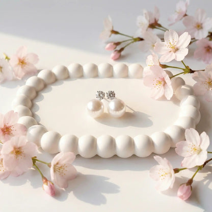Pearl Drop Earrings with crystal studs displayed on white ceramic tray with soft sunlight and floral accents