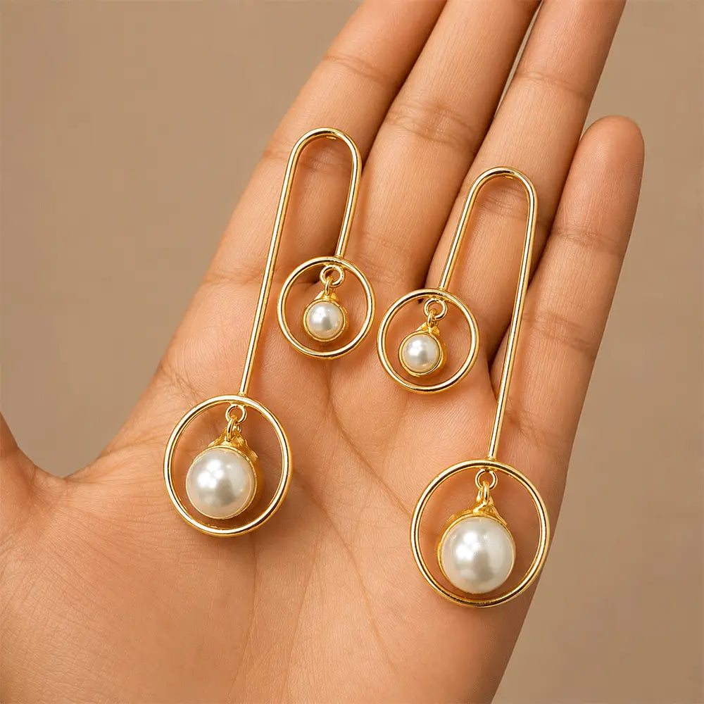 Pair of Pearl Orbit anti tarnish brass earrings with modern gold-toned circular frames and suspended white pearl drops.
