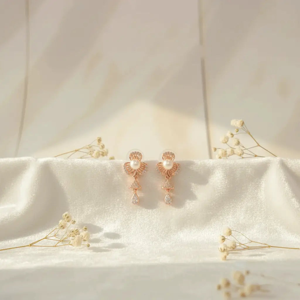 Rose gold pearl petal AD earrings displayed on soft white fabric with baby’s breath flowers.