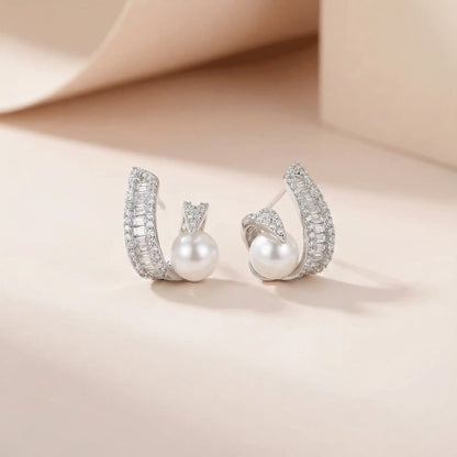 Elegant anti tarnish pearl swirl earrings in silver finish with crystal accents on beige studio background