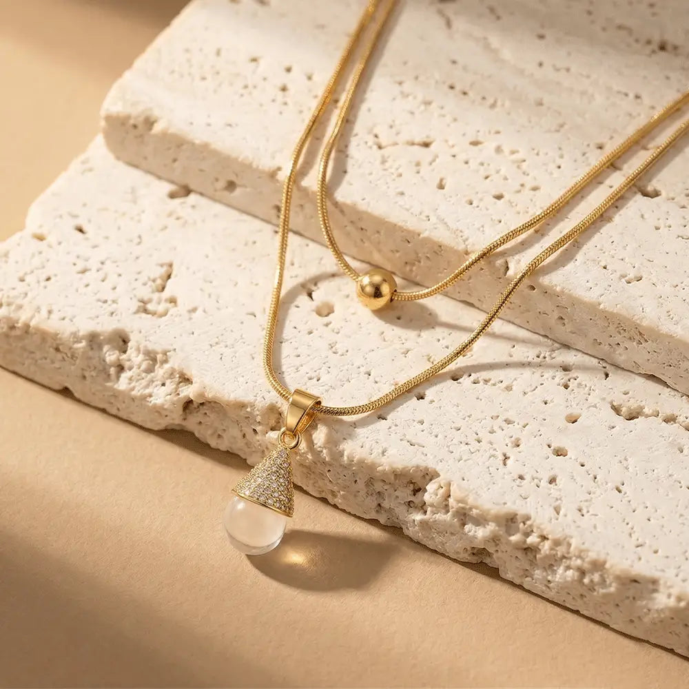 Minimal gold pearl pendant layered necklace on beige stone surface, anti-tarnish everyday jewelry by Ka Trends
