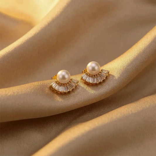 Pearl Fan AD Studs with gold accents on a beige fabric background