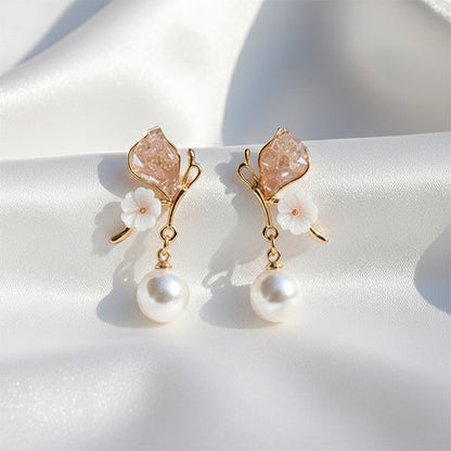 Petal pop pearl drop earrings in gold finish displayed on white satin