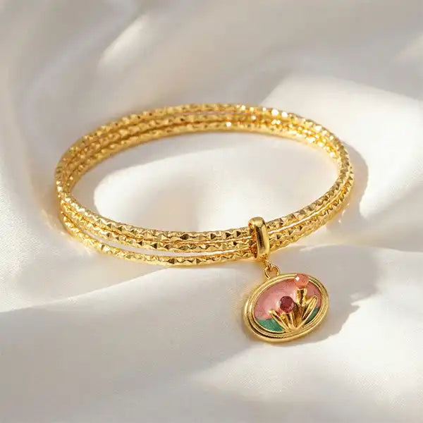 Pink Charm Bangle Bracelet displayed in full circular shape with floral charm on satin background