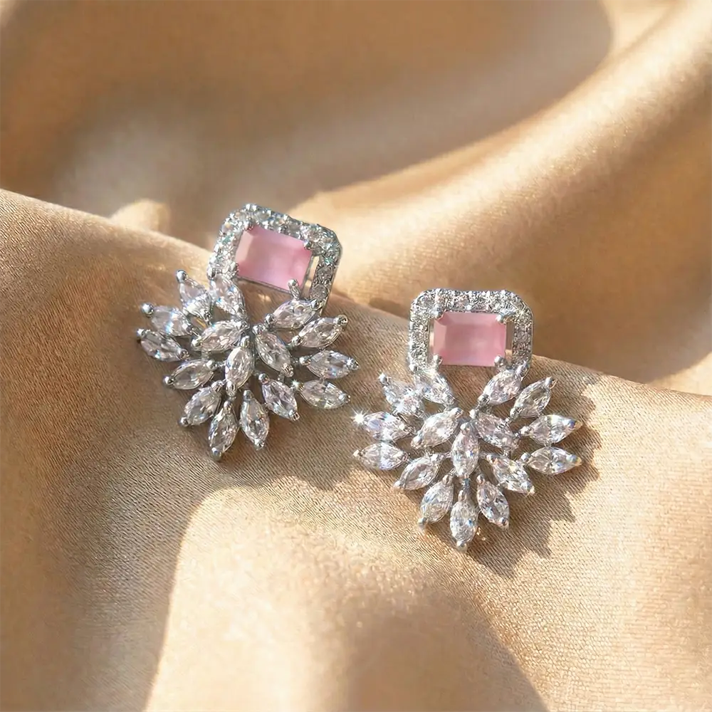A pair of Pink Petal American diamond stud earrings displayed on soft gold satin fabric.