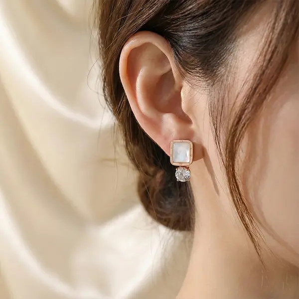 Rose gold square drop earrings with white stone and crystal worn on ear, minimal elegant design
