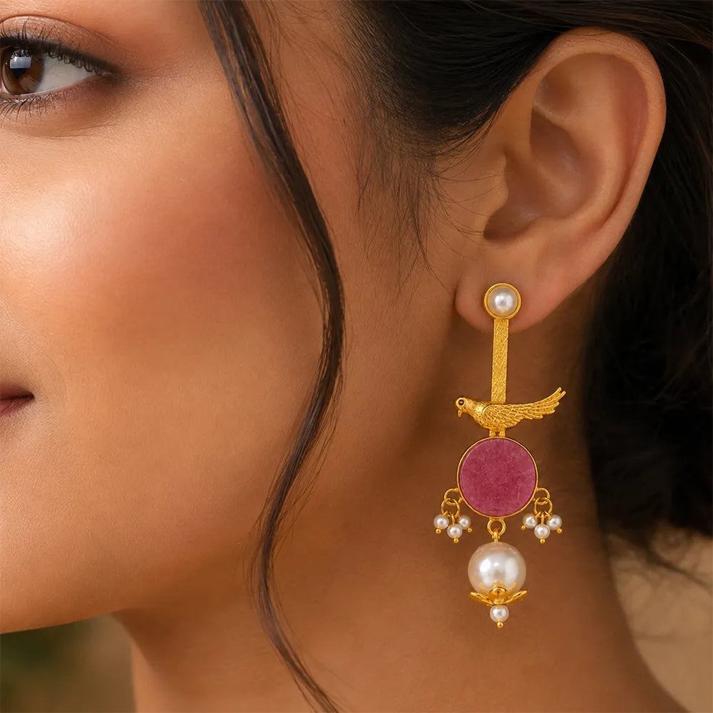 Indian model wearing Rosy Sparrow anti tarnish brass earrings featuring a pink gemstone, bird motif, and pearl drop design.