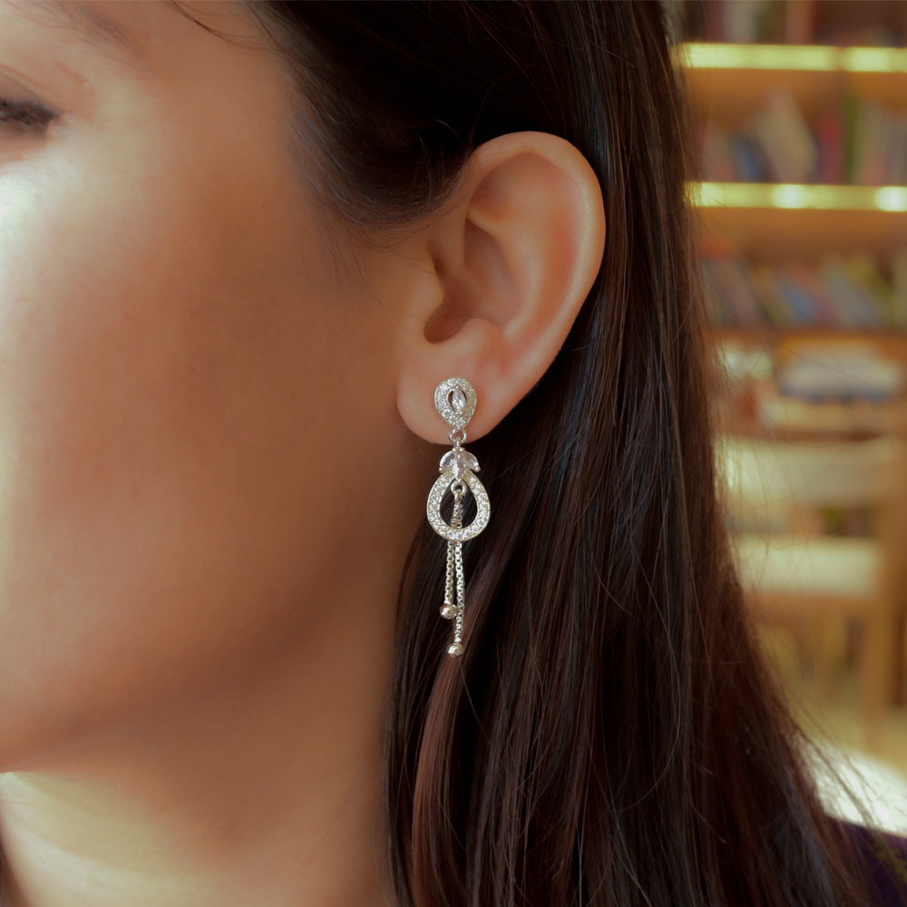 Close-up of a woman wearing a Shiny AD Danglers with a blurred bookshelf background