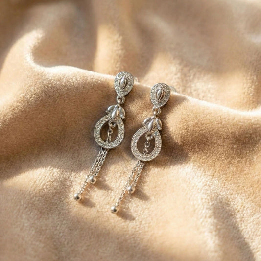 Shiny AD danglers earrings with chain details on a beige fabric background