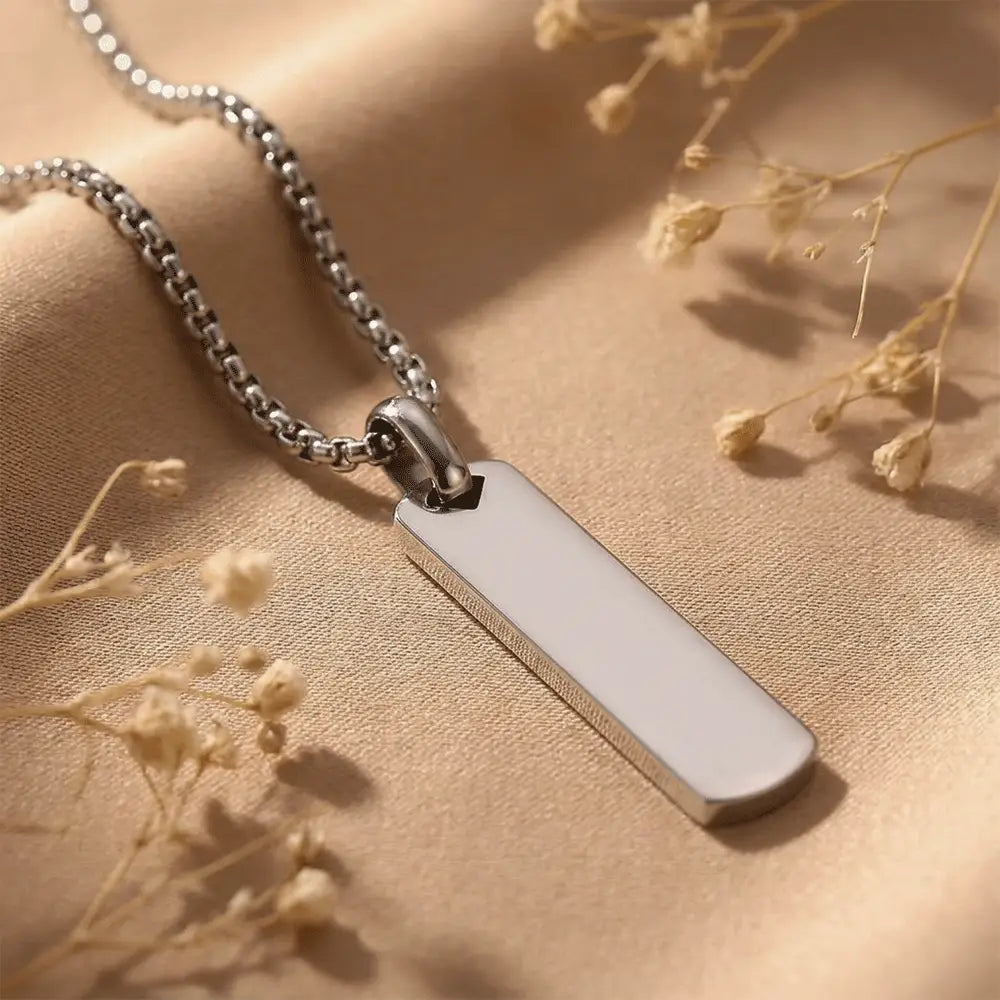 Close-up of premium silver anti-tarnish bar pendant necklace on soft beige fabric background by K-A Trends
