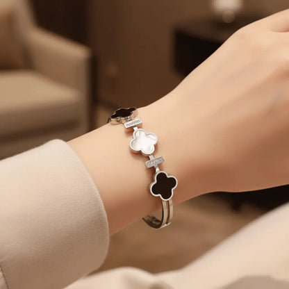 Silver Clover Bracelet with enamel clover motifs and crystal accents worn on wrist against a beige backdrop.