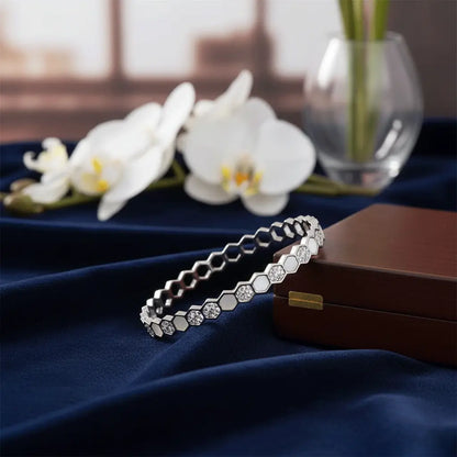 Silver hexagon charm bracelet with sparkling stones displayed on blue velvet with orchid flowers and jewellery box – K-A Trends luxury bracelet.