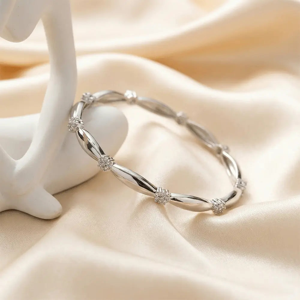 Close up of silver knot AD bangle in polished finish, lightweight anti tarnish bracelet for daily wear