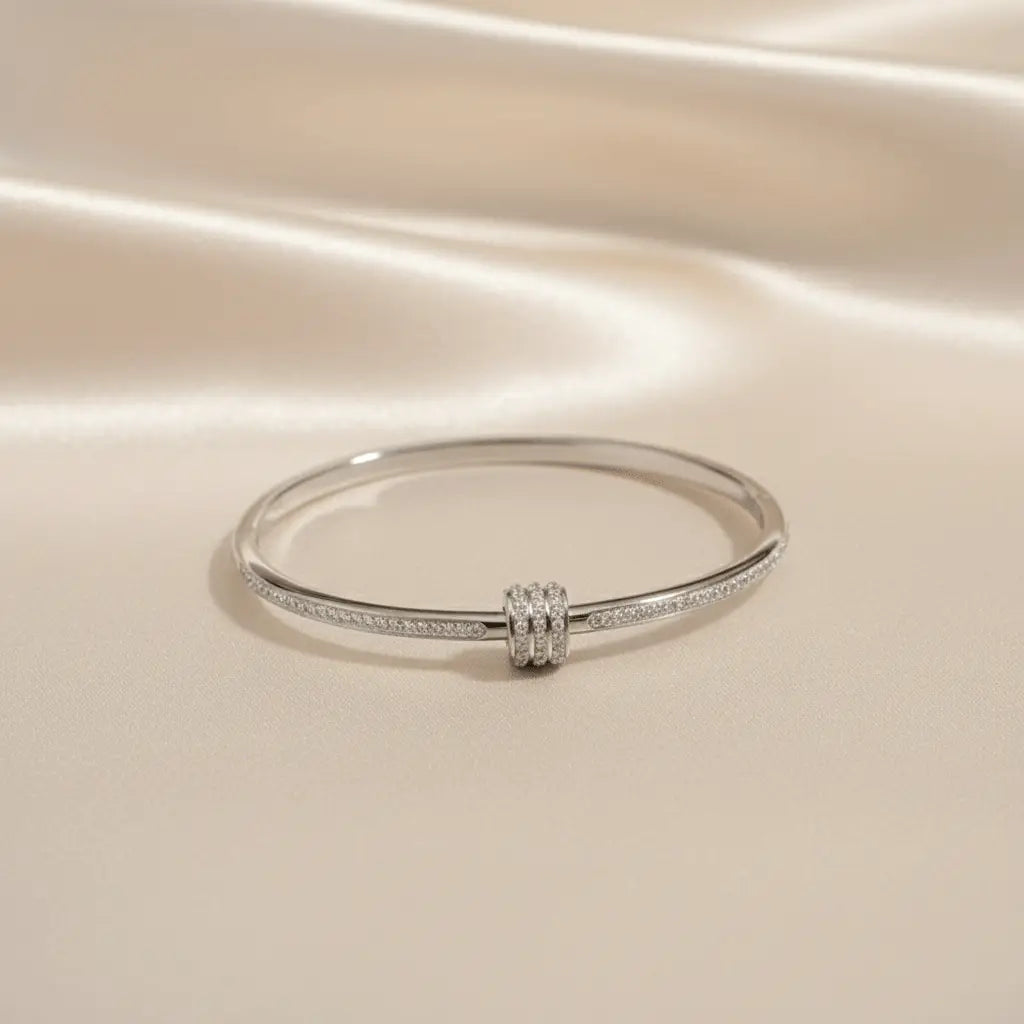 Silver anti-tarnish bangle bracelet with triple-ring charm displayed on beige satin background – K-A Trends jewellery.