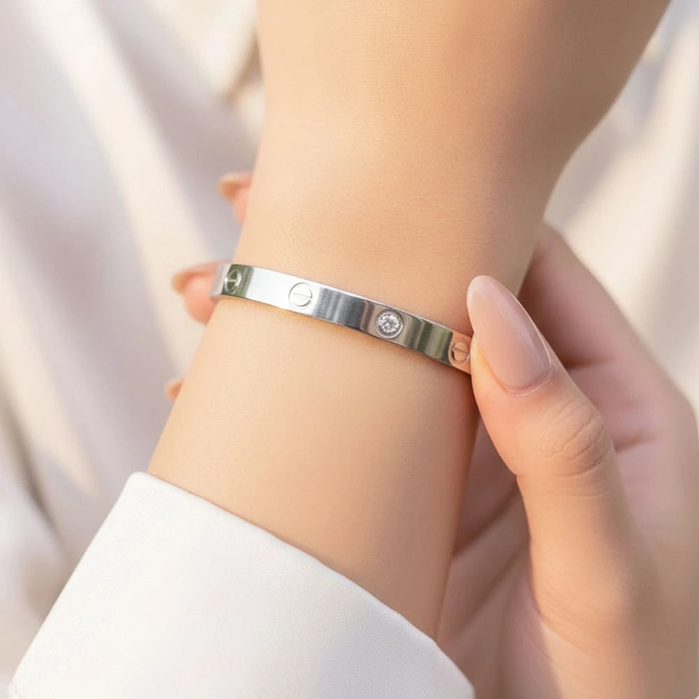 Silver cartier bracelet with a diamond on a wrist against a blurred background