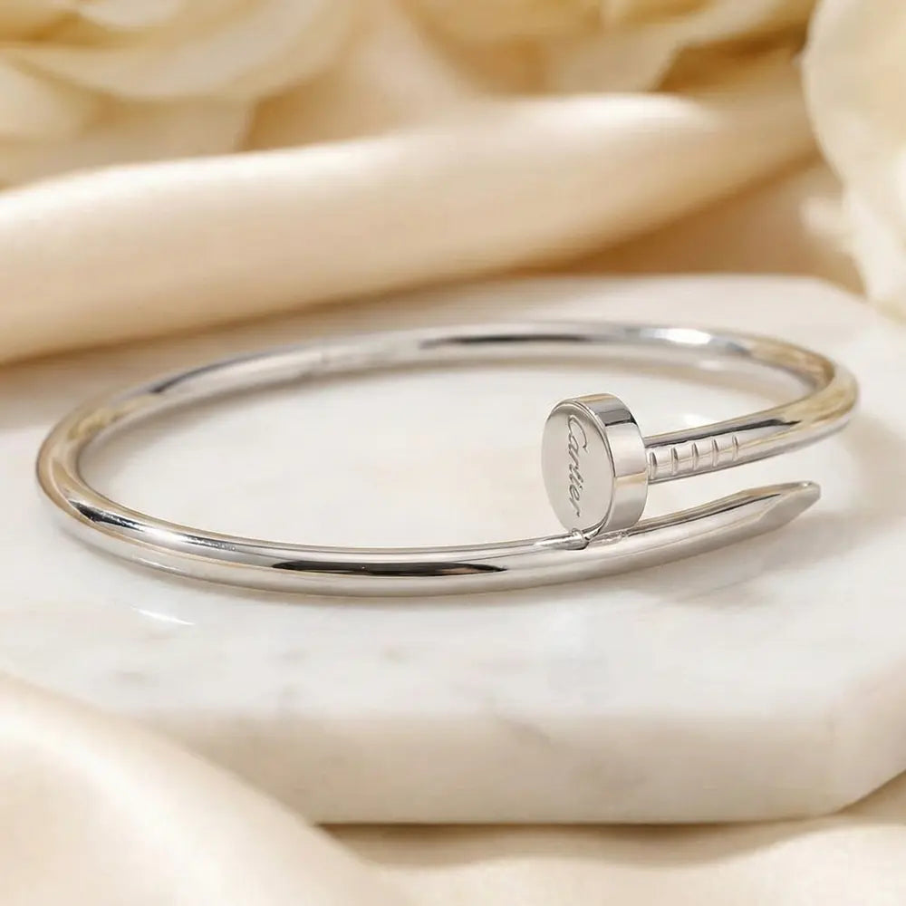 Silver Nail Bracelet with engraved text on a beige fabric background