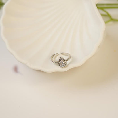 Silver teardrop ring with a diamond on a white shell