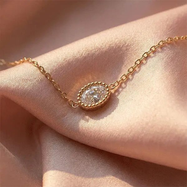 Sparkle Chain Pendant Necklace in rose-golden colour featuring an oval crystal charm displayed on soft pink satin.