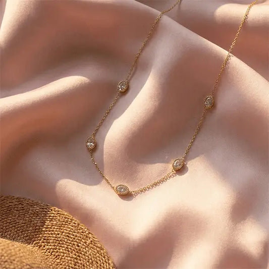 Rose-golden Sparkle Chain Pendant Necklace with multiple oval crystal stations styled on pink satin under warm sunlight.