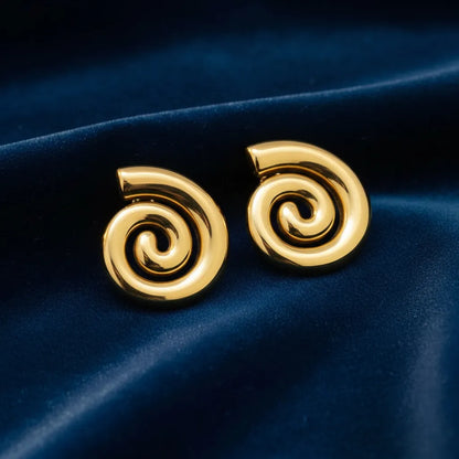 Pair of bold, anti-tarnish gold spiral stud earrings on a cream-colored surface.