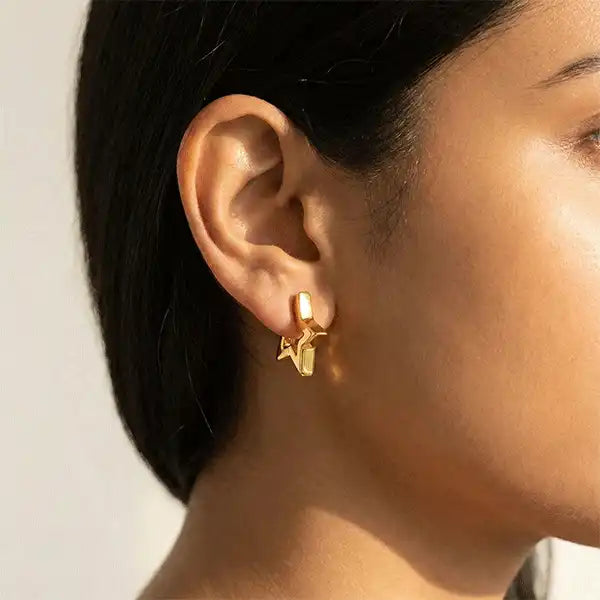 Indian woman wearing gold star hoop earrings, close-up ear shot in natural sunlight