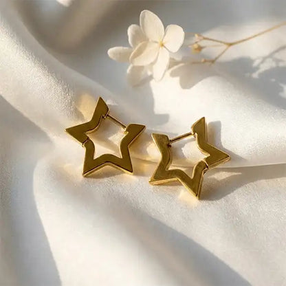 Gold star hoop earrings flat lay on white satin background with natural light