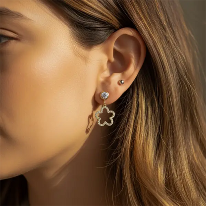 Woman wearing Starlit Clover Dangles in golden finish, featuring a crystal stud and clover-shaped drop design.