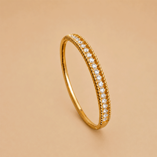 Stone Bangle bracelet featuring a single row of sparkling clear pavé stones, displayed on a warm beige background.