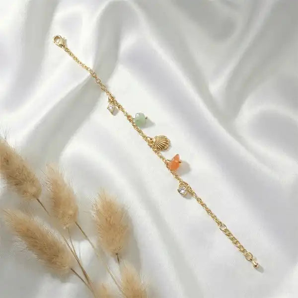 Gold anti-tarnish stone charm bracelet with pastel crystal charms on white satin background