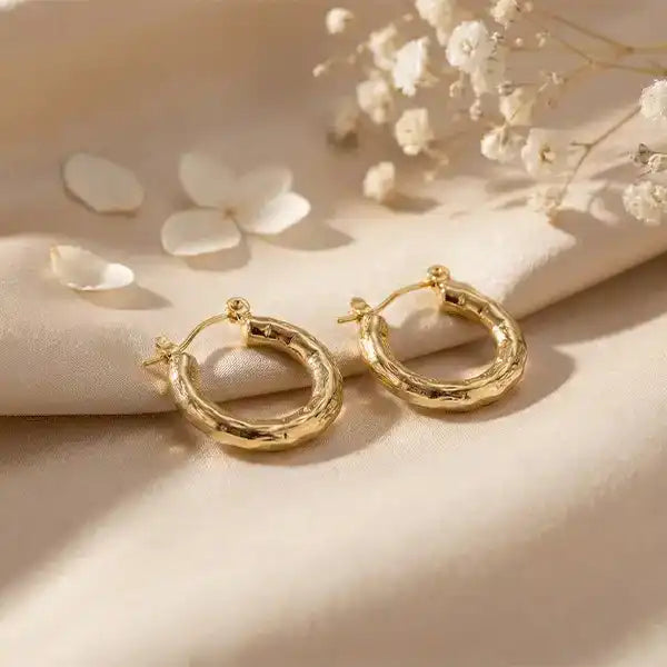 Textured Gold Bali Hoop Earrings placed on white satin fabric