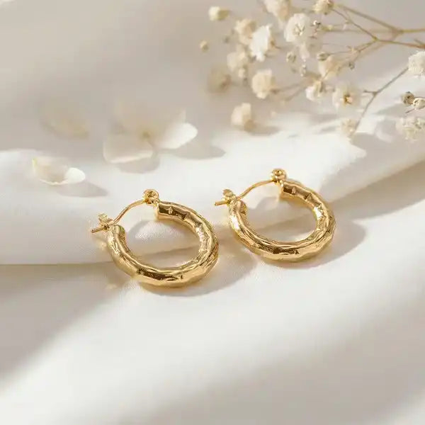 Textured Gold Bali Hoop Earrings with soft sunlight on satin background